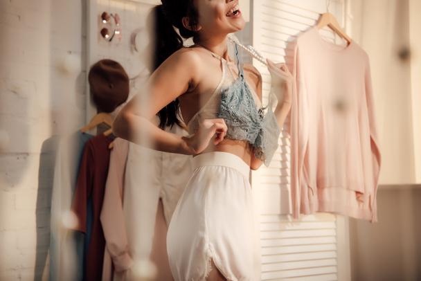 Schnappschuss einer glücklichen jungen Frau bei der Kleiderwahl im Kleiderschrank - Foto, Bild