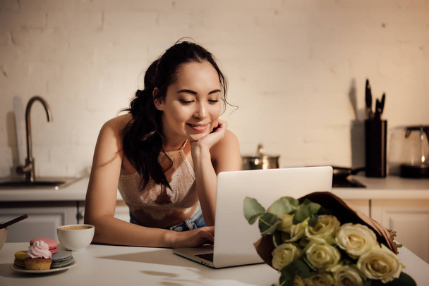 усміхнена молода азіатська жінка використовує ноутбук вдома
 - Фото, зображення