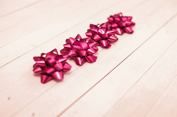 Set of decorative magenta bow over wooden background with space for text. - Photo, Image