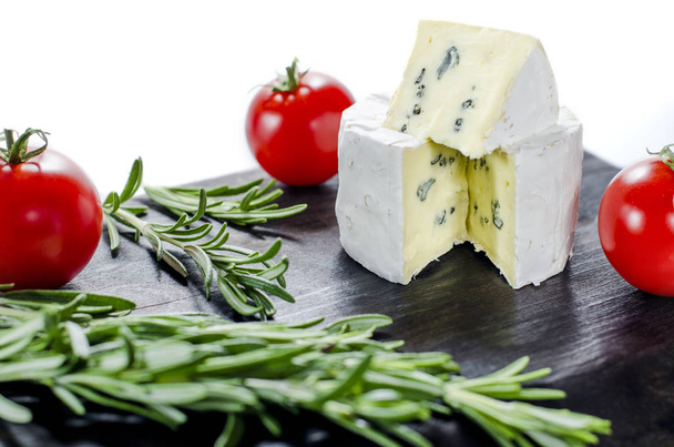 Асорті сирів на дерев'яній дошці. Камамбер, сир з синьою цвіллю, моцарелла з помідорами та розмарином
 - Фото, зображення