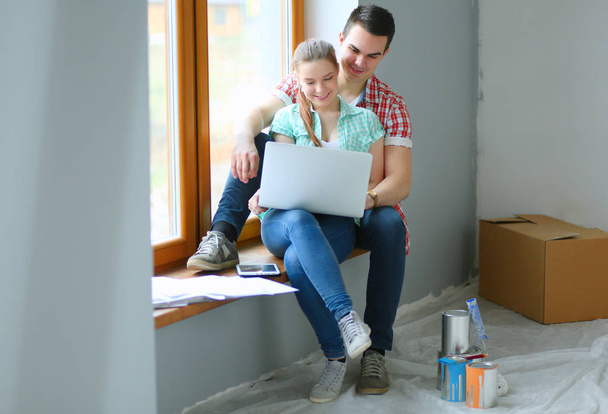 Couple moving in house sitting on the windowsill with laptop - Foto, Bild