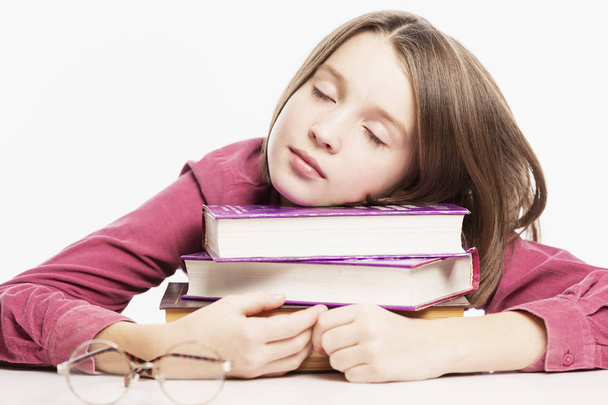 Teen girl sleeping on a stack of books, close-up, white background - Fotoğraf, Görsel