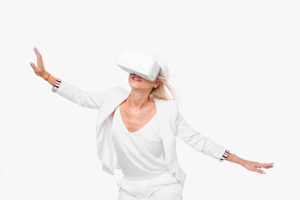 Blond woman in white suite with virtual reality goggles. Studio shot on white background - Fotografie, Obrázek
