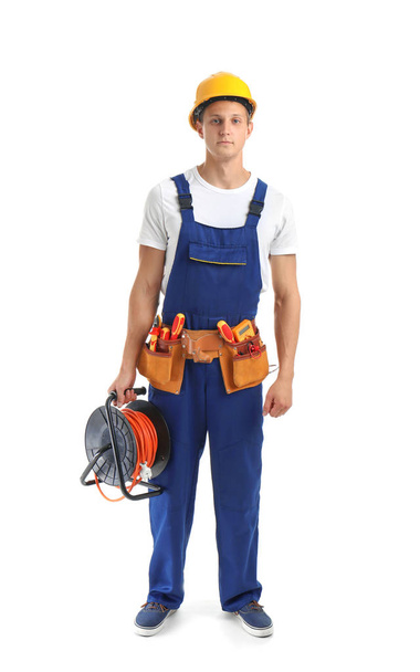 Electrician with extension cord reel and tools  wearing uniform on white background - Foto, afbeelding