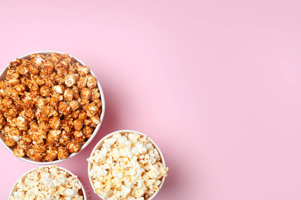 Different kinds of popcorn on color background, top view. Space for text - Foto, afbeelding