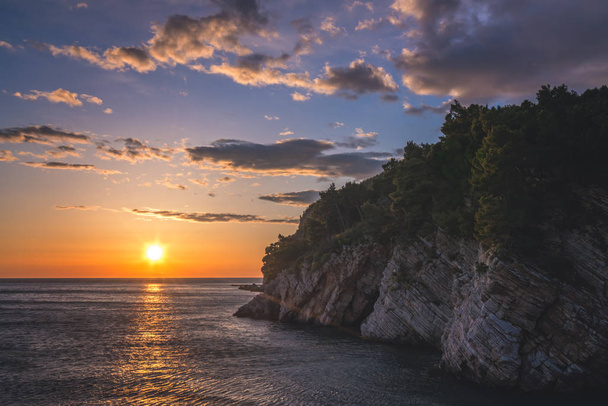 Ηλιοβασίλεμα πάνω από τα βράχια στην ακτή του Petrovac, Μαυροβούνιο - Φωτογραφία, εικόνα