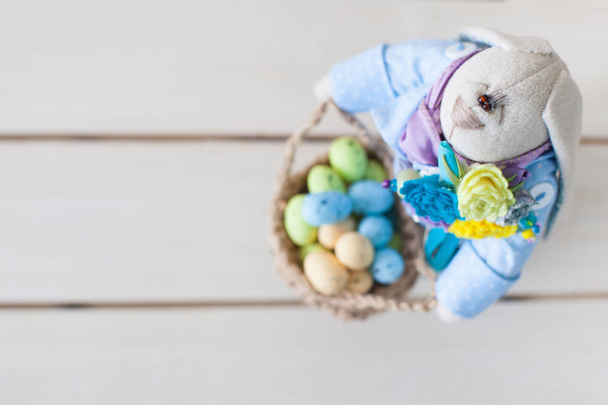 Handmade toys. Easter rabbit. Multicolored eggs. White background. Nest with eggs. - 写真・画像
