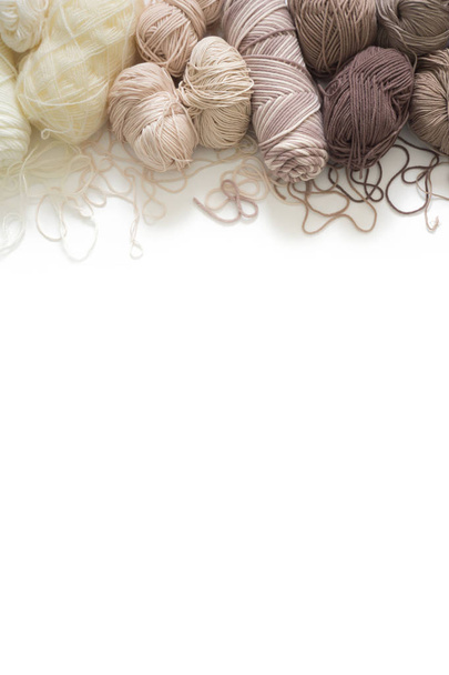 The yarn is beige, brown, gray and white. Knitting needles, scissors, knitting, knitted fabric. - Valokuva, kuva