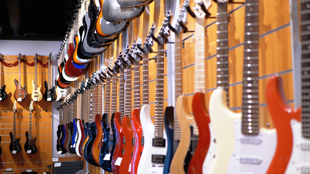 Wiele gitar elektrycznych, wiszące w sklepie muzycznym. Instrumenty muzyczne sklep - Materiał filmowy, wideo