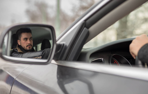 Handsome young man driving car photographed in rear view mirror in winter - Zdjęcie, obraz