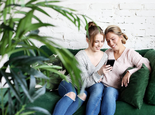  Aged woman and her adult daughter using smartphone at home. - Foto, imagen