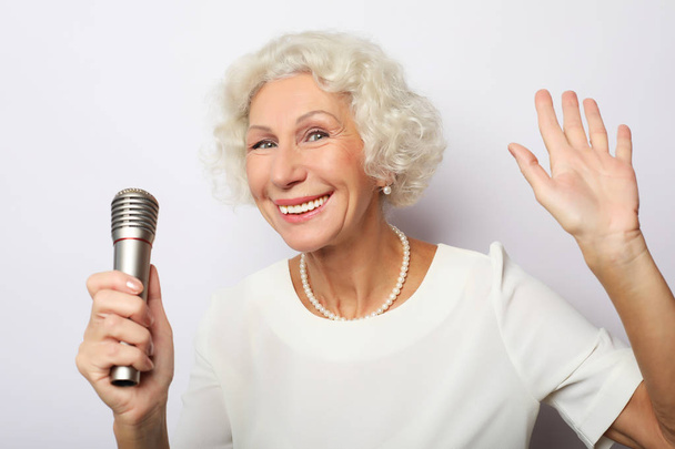 Portrait of charming modern grandmother holds up the microphone  - Фото, изображение