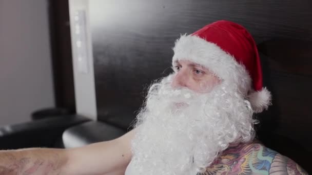 Fitness instructor Santa Claus in the gym resting on a leather sofa. - Záběry, video