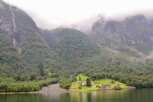 Fő nézet-a falu Styvi és a mezőgazdasági Múzeum a környező vízesések a háttérben. Ónos falu található a nyugati parton a Nærøyfjord északra Gudvangen village, Norvégia. - Fotó, kép