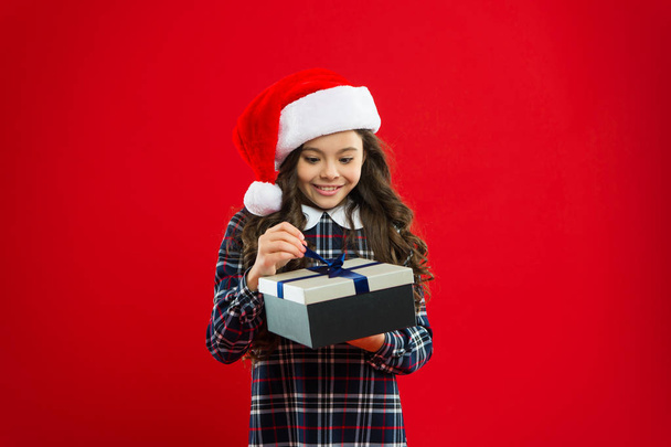Christmas shopping. Little girl child in santa red hat. Present for Xmas. Childhood. Great gift. New year party. Santa claus kid. Happy winter holidays. Small girl. interested what is inside - Foto, Imagen