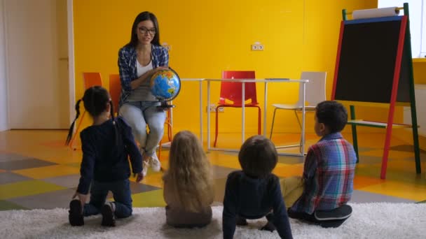 Vorschullehrerin lehrt Kinder über Globus - Filmmaterial, Video