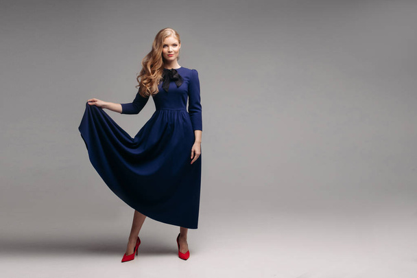 Εντυπωσιακά λεπτό μοντέλο σε φωτεινό μπλε φόρεμα και μαύρο τακούνια. - Φωτογραφία, εικόνα