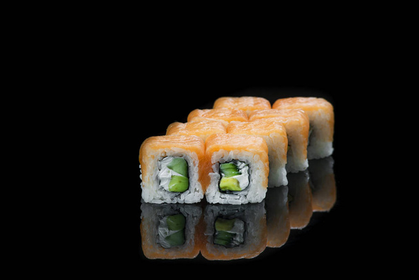 Sushi rolls with salmon, tuna, cucumber and green onions on black background - Photo, Image
