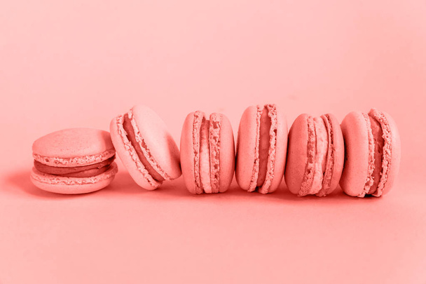Sweet almond macaron or macaroon dessert cake colored in trendy color of year 2019 Living Coral background. Bright Macro color 16-1546. Minimal food bakery concept. Flat lay top view copy space - 写真・画像
