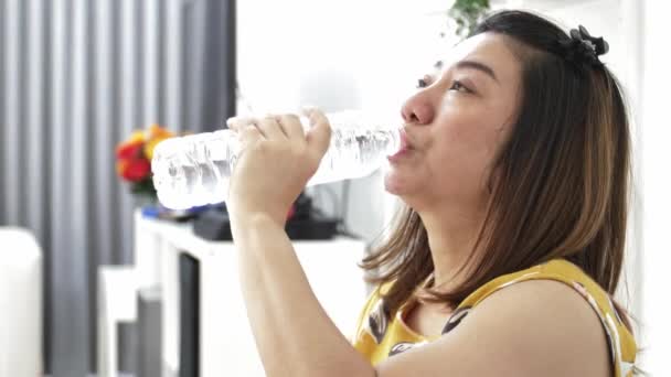 Asian kobieta pije wodę mineralną z butelki. Piękna dziewczyna z długimi włosami napoje czystej wody. Zwolnionym tempie 4k - Materiał filmowy, wideo
