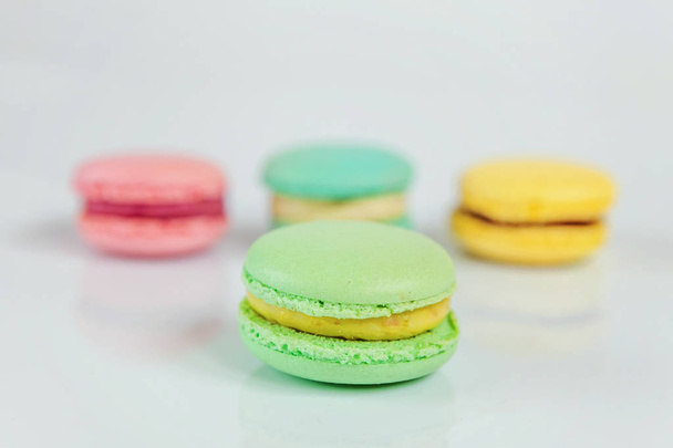 甘いアーモンド カラフルなピンク、青、黄色、緑のマカロンや白い背景で隔離のマカロン デザート ケーキ。フランスの甘いクッキー。最小限の食べ物ベーカリー コンセプト。コピー スペース - 写真・画像