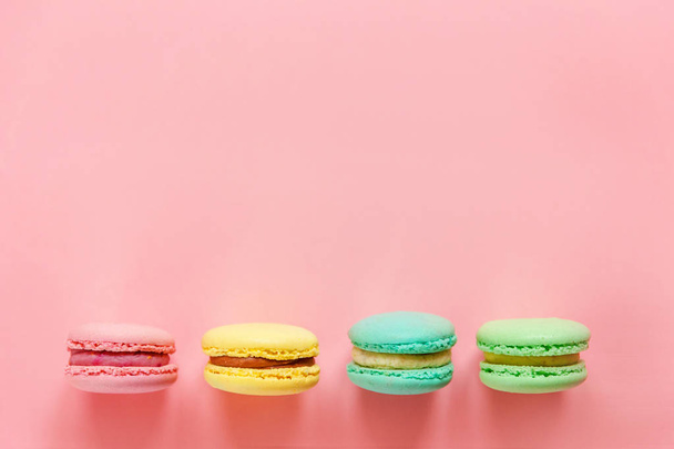 Sweet almond colorful pink blue yellow green macarons or macaroon dessert cake isolated on trendy pink pastel background.  - Фото, зображення