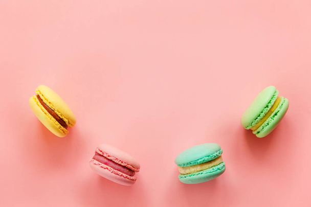 Doce amêndoa colorido rosa azul amarelo verde macarons ou bolo de sobremesa macaroon isolado no fundo pastel rosa na moda
.  - Foto, Imagem