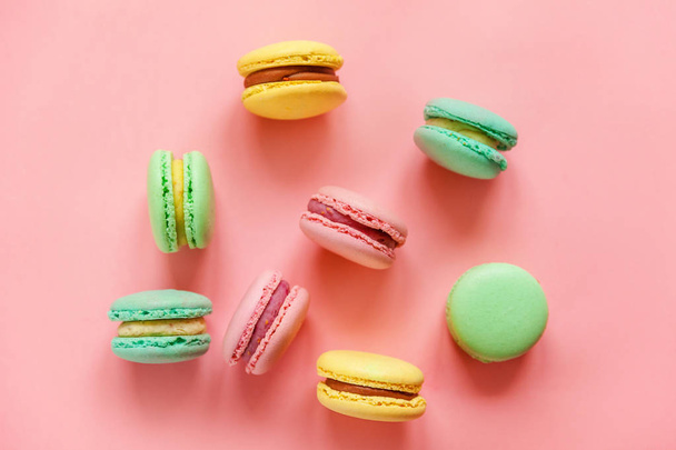 Sweet almond colorful pink blue yellow green macarons or macaroon dessert cake isolated on trendy pink pastel background.  - Fotoğraf, Görsel