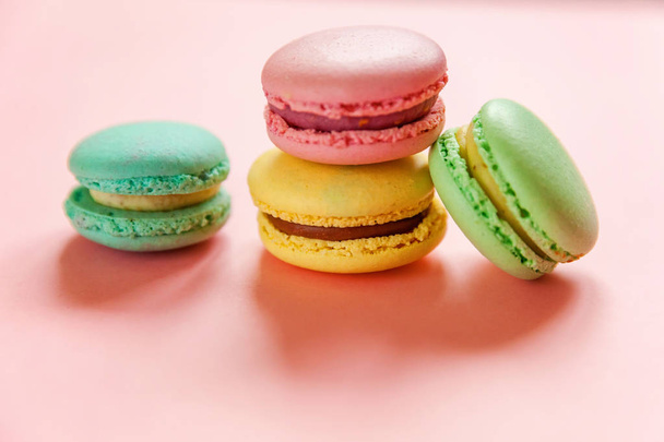 Sweet almond colorful pink blue yellow green macarons or macaroon dessert cake isolated on trendy pink pastel background.  - Photo, Image