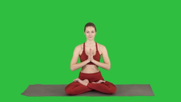 Beautiful young woman sitting in yoga pose Lotus changing position of her hands on a Green Screen, Chroma Key. - Footage, Video