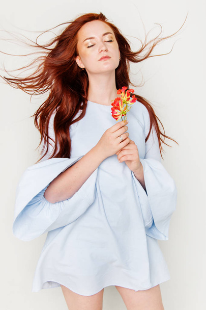 joven hermosa mujer tiene pelo rojo creativo oro maquillaje están posando en un estudio con flores
 - Foto, Imagen