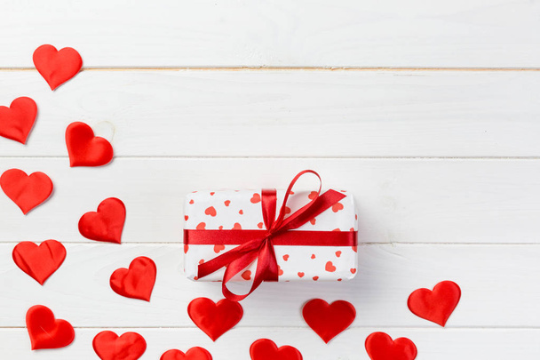 San Valentín u otro regalo hecho a mano en papel con corazones rojos y caja de regalos en envoltorio de vacaciones. Regalo de caja de regalo en vista superior de mesa de madera blanca con espacio de copia, espacio vacío para el diseño
. - Foto, Imagen