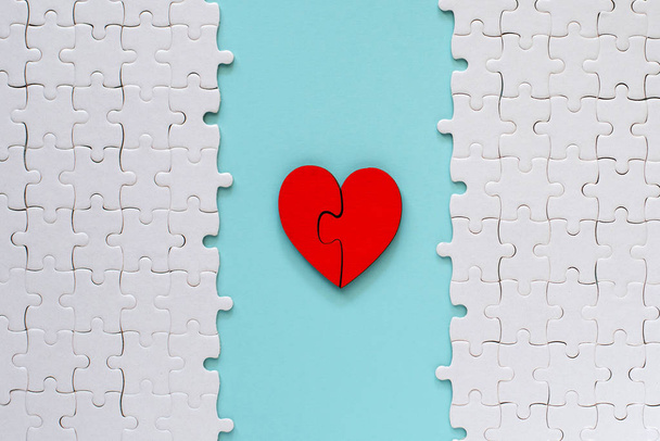 dos piezas de corazón de amor rompecabezas rojo con rompecabezas blanco sobre fondo azul, concepto de amor
. - Foto, Imagen