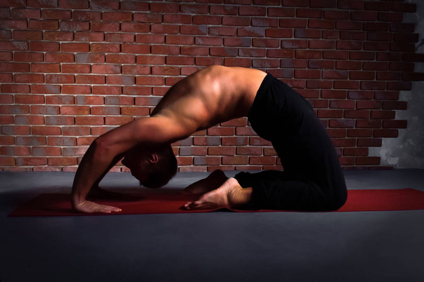  Young man doing the pose of yoga Kapotasana - Foto, Imagen