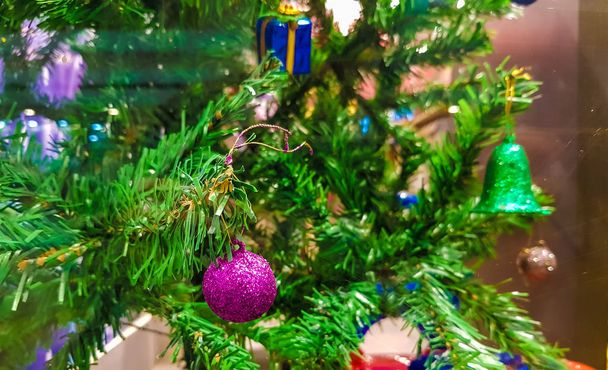 árbol de Navidad verde decorado con coloridas campanas de bolas y cajas de regalo
 - Foto, imagen