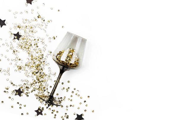Black wine glasses with golden confetti and black stars on white background. Flat lay, top view. Holyday and celebration concept. - Фото, зображення