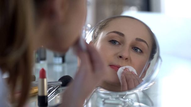 Sad girl removing her bright makeup looking at reflection, unsuccessful date - Foto, imagen