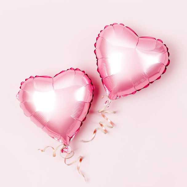 Air Balloons of heart shaped foil  on pastel pink background. Love concept. Holiday celebration. Valentine's Day or wedding/bachelorette party decoration. Metallic balloon - Фото, изображение
