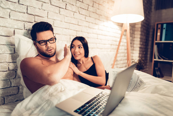 Young Couple in Bed, Man Working Laptop Bored Wife - Foto, afbeelding