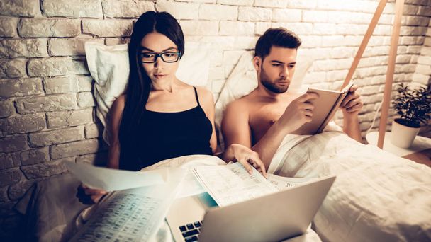 Couple Using Laptop Reading Book Before Sleeping - Foto, immagini