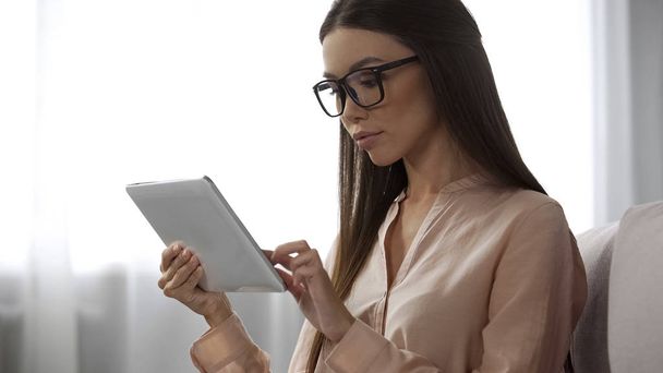 Elegant lady in glasses analyzing email letters, checking inbox folder on tablet - Foto, Imagen