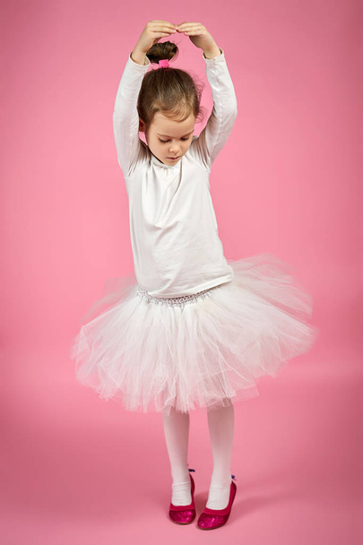 portrait of a cute little girl in tulle skirt on a pink background - Foto, immagini