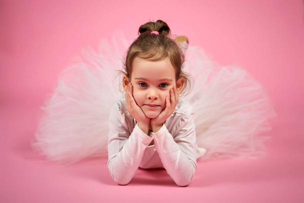 portrait of a cute little girl in tulle skirt on a pink background - Foto, Imagen