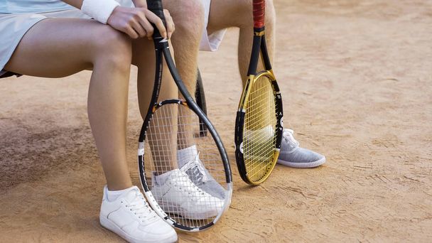 Молодые теннисисты ждут матча на скамейке запасных, ноги крупным планом
 - Фото, изображение