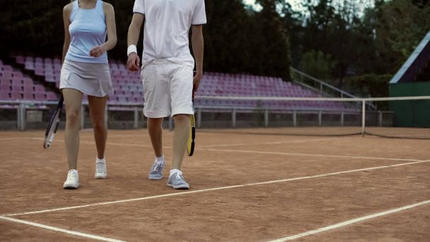 Young male and female tennis players walking on court, after match, close up - Фото, зображення