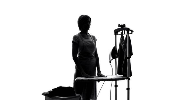 Housewife in apron standing near ironing board, laundry service, housework help - Fotografie, Obrázek