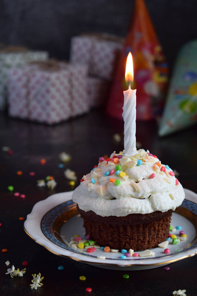 キャンドル バニラ クリームとチョコレートのカップケーキ。お誕生日おめでとう。暗い写真. - 写真・画像
