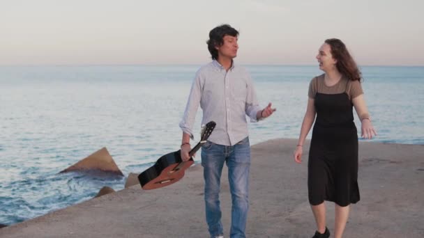 Para piękny muzyk chodzić spacer po molo nad morzem - Materiał filmowy, wideo