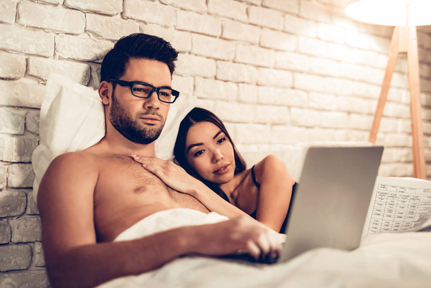 Couple Using Laptop Lying on Bed Watching Movie - Fotografie, Obrázek