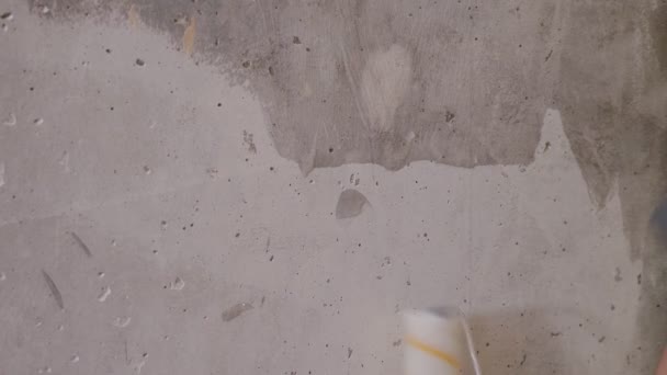 Cosechadora aplicando pegamento en pared de hormigón desnudo con rodillo de pintura
  - Metraje, vídeo